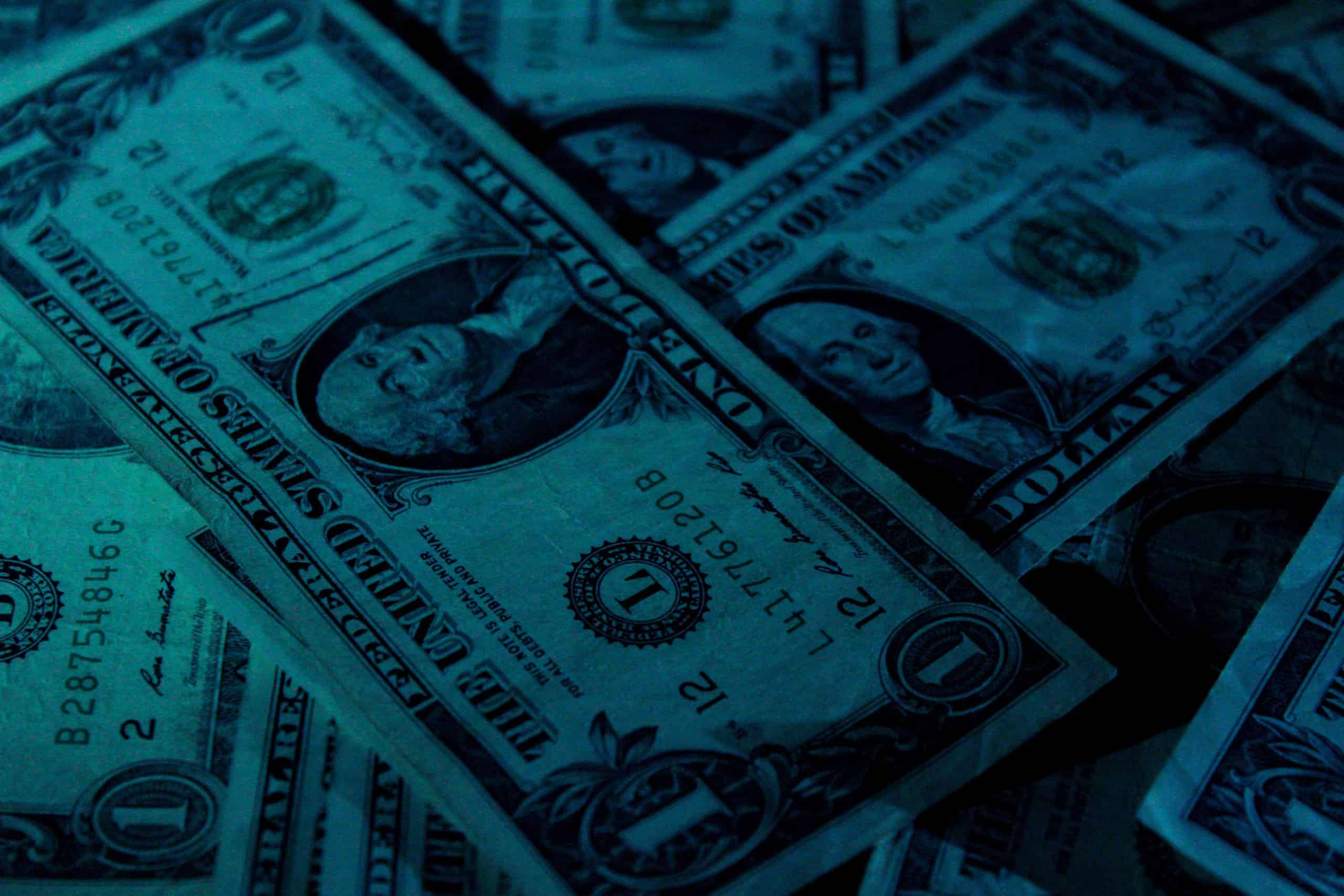 a pile of one dollar bills in dim lighting