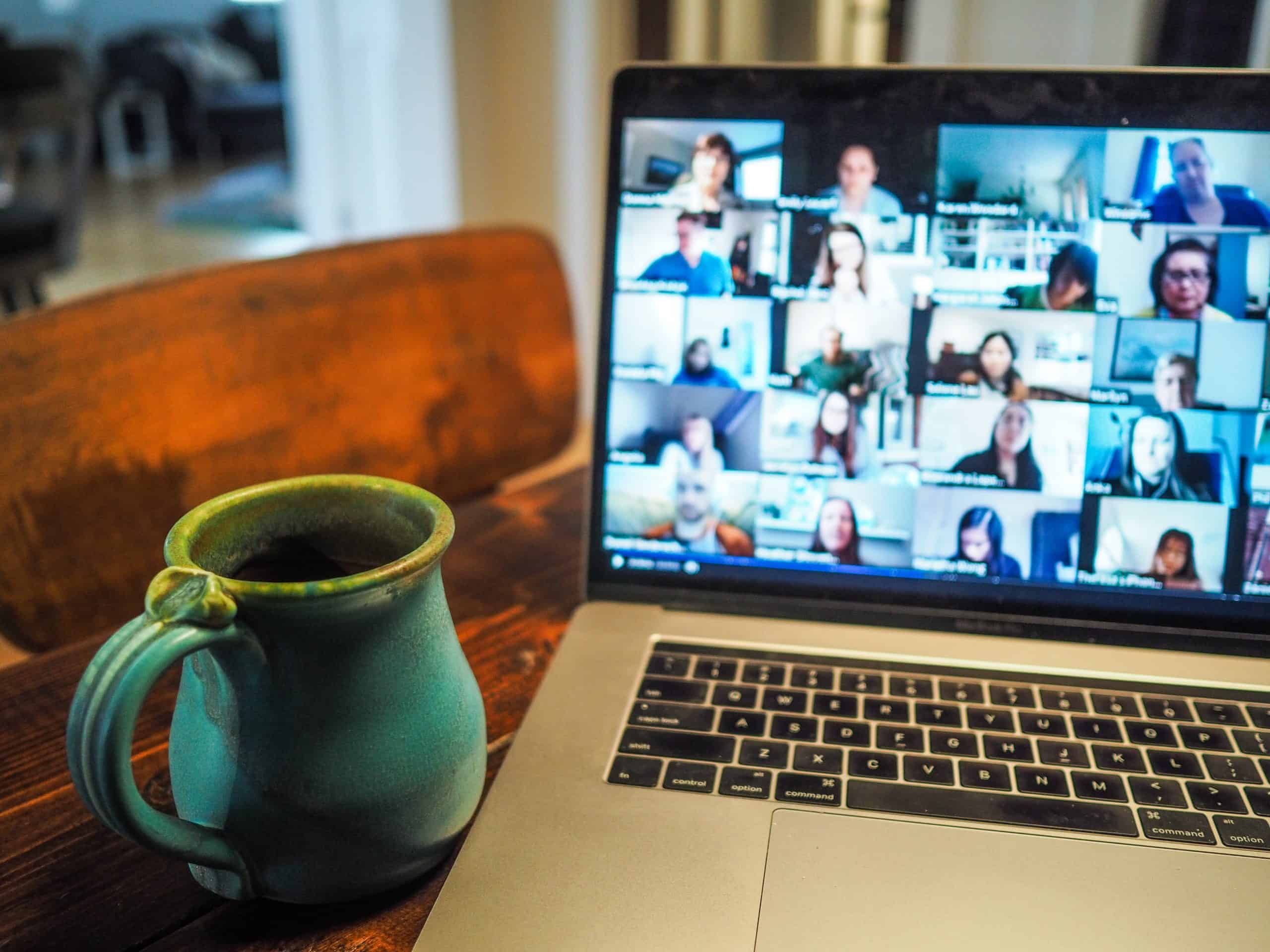 uma caneca de café na frente de um computador durante uma reunião virtual